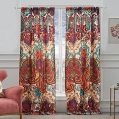 a living room filled with furniture and a window covered in paisley print curtain panels, along with a pink chair