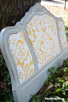 a white and yellow bed sitting next to a tree