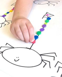 a child's hand on a beaded spider craft