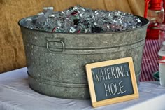 a bucket full of ice sitting on top of a table next to a chalk board