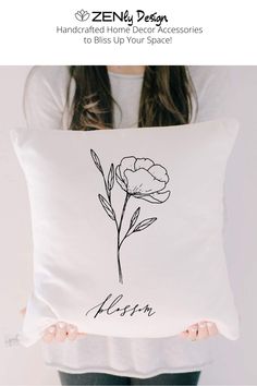 a woman holding a pillow with a flower drawn on it