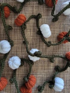 crocheted carrots and cotton balls are arranged on a tablecloth with twine