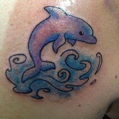 a dolphin tattoo on the back of a woman's shoulder