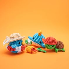 three crocheted toy animals sitting next to each other on an orange background,