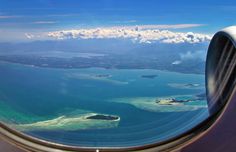 the view from an airplane window looking out at some water and land in the ocean