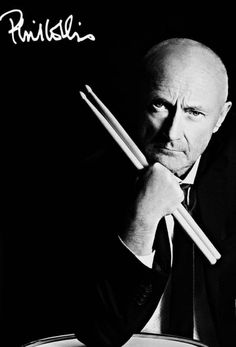 a man holding two chopsticks in front of his face while leaning on a drum