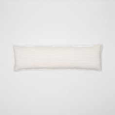 a white and beige striped pillow on a white wall