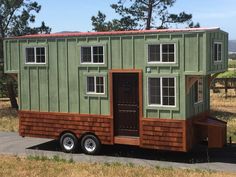 a small green and brown house sitting on the side of a road