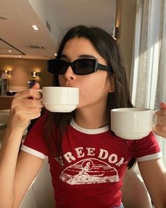 a woman wearing sunglasses drinking from a cup