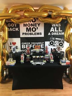 a black table topped with gold balloons next to a sign that says money mo '