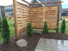 a wooden fence in the middle of a yard with trees and rocks on the ground