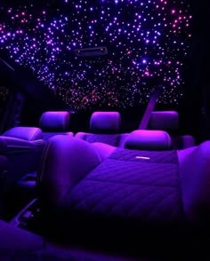 the interior of a car with purple and blue lights shining on the ceiling, along with leather seats