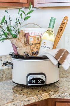 a crock pot filled with wine, cheese and other items on a kitchen counter