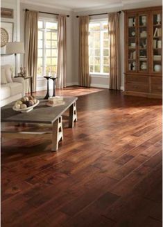 a living room filled with furniture and wooden flooring next to two large open windows