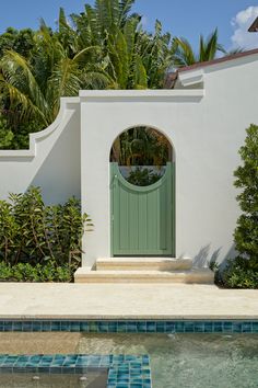 a house with a pool in front of it and a green door on the side