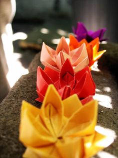 three origami flowers sitting on top of a rock