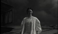 a black and white photo of a woman walking down the street with her hand in her pocket