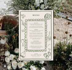 a menu sitting on top of a table next to flowers and potted greenery