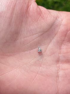 a person's left hand holding a tiny diamond