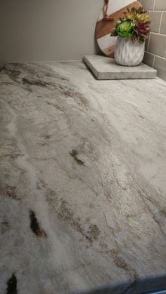 a marble counter top in a bathroom next to a vase with flowers