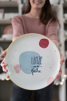 a woman holding up a plate with some writing on it