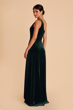 a woman in a long green dress is looking back at the camera and she has her hands on her hips