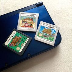 three gameboy games sitting on top of a blue laptop computer screen next to each other