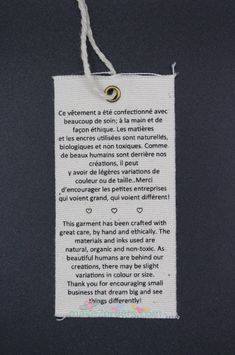 a piece of paper hanging from a string with a poem written in french on it