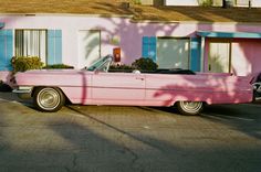 a pink car parked in front of a house