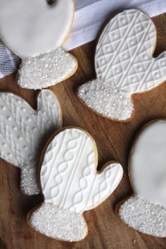 four decorated cookies sitting on top of a wooden cutting board