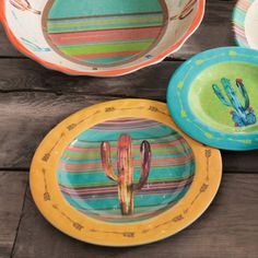 colorful plates with cactus designs on them sitting on a wooden table next to each other