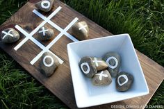 rocks are arranged in a bowl on the grass next to a tic - tac - toe board