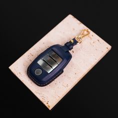 a blue car keychain sitting on top of a piece of wood