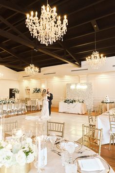 a bride and groom standing in front of a chandelier at their wedding reception