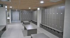 a row of lockers in a public restroom with benches and lights on the ceiling