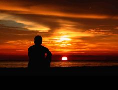 a man standing on the beach at sunset