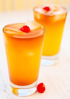 two glasses filled with drinks sitting on top of a table