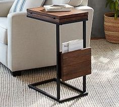 a white couch sitting next to a wooden end table on top of a carpeted floor