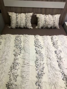 a bed with white and silver pillows on top of it