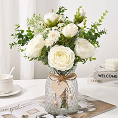 a vase filled with white flowers sitting on top of a table next to a book