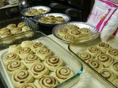 several pans filled with cinnamon rolls sitting on top of a counter