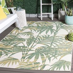 a green and white area rug sitting on top of a wooden floor next to plants