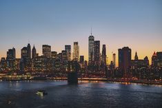 the city skyline is lit up at night as seen from across the river in new york