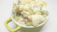 a green bowl filled with potato salad on top of a white table