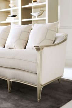 a white couch sitting on top of a carpeted floor next to a book shelf