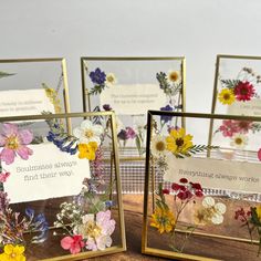 three framed pictures with flowers on them sitting on a wooden table next to each other