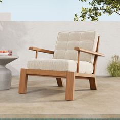 a wooden chair sitting on top of a tile floor next to a table and potted plant