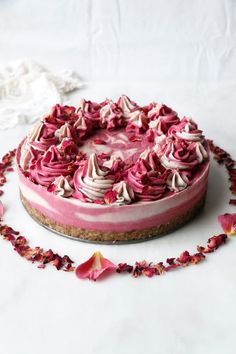 a pink and white cheesecake with flowers on the top is sitting on a table