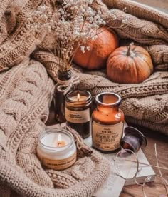 pumpkins and candles are sitting on a blanket