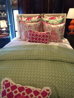 a bed with green and pink comforter, pillows and lamps on the nightstands